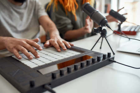 Close up of hands of man making music using equipment, drum pad machine. Female and male bloggers recording video blog or vlog at homeの写真素材