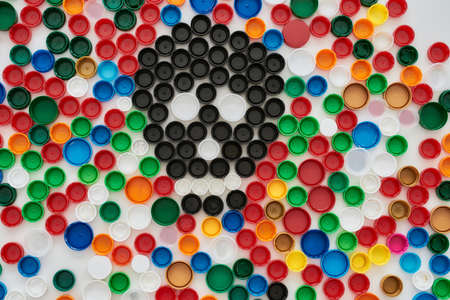 Flatlay collage with colorful plastic bottle caps and skull made of black caps on white background....