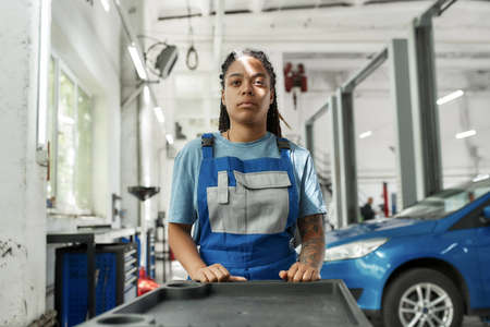 Exploring repairing. African american woman, professional female mechanic pulling, carrying tool box...