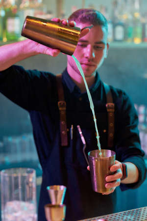 Bartender do it better. Close up of male bartender pouring, mixing ingredients while making cocktail...