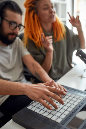 Focus on hands of man making music using equipment, drum pad machine. Female and male bloggers recording video blog or vlog at homeの写真素材