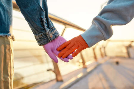 Close up of hands of lesbian couple. Two girls holding their hands, wearing protective gloves,...