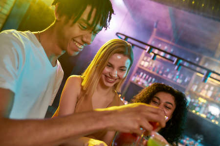 Fill yourself with fun. A group of friends, young women and man smiling while having fun, drinking...