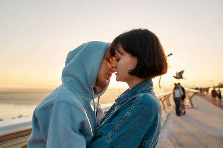 Lesbian couple hugging on the bridge, going to kiss while admiring the sunrise together