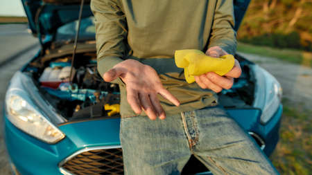 Close up of hands of man driver wiping his hands off after repairing broken car on the road sideの写真素材