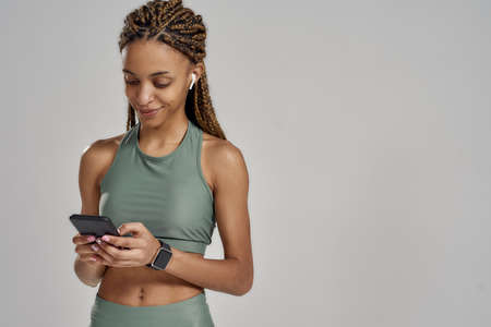 Listening music after workout. Young beautiful mixed race woman wearing wireless headphones using...