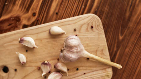 Top view of clove of garlic with peppercorn on the wooden chopping board