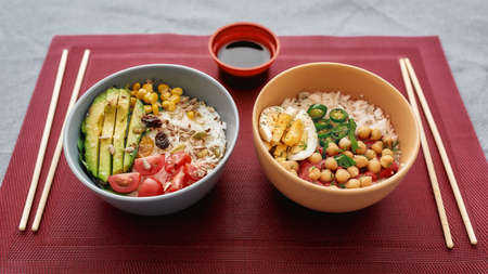 Close up of two bowls with sliced vegetables and rice served on napkinの写真素材
