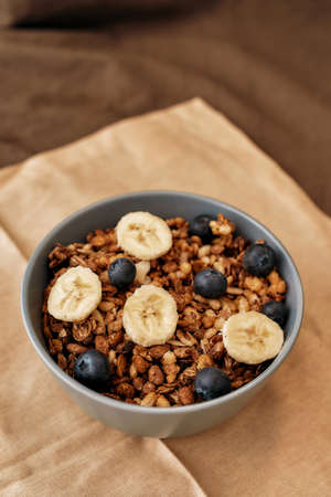 Close up of homemade granola in a plate with nuts, honey, blueberries, banana and other natural...