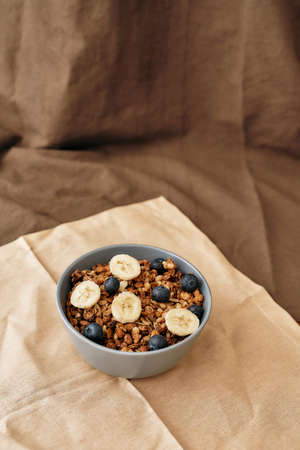 Homemade granola in a plate with nuts, honey, blueberries, banana and other natural ingredients...