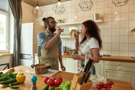 Italian man looking at his girlfriend while they are drinking white wine. Chef cook using hand...