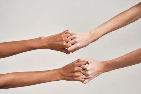 Close up of female hands holding together with fingers crossed isolated on greyの写真素材