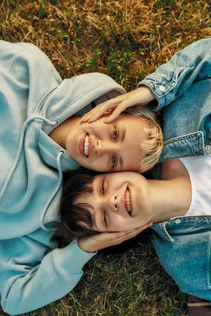 Top view of happy lesbian couple smiling at camera, touching each other face while lying on the...