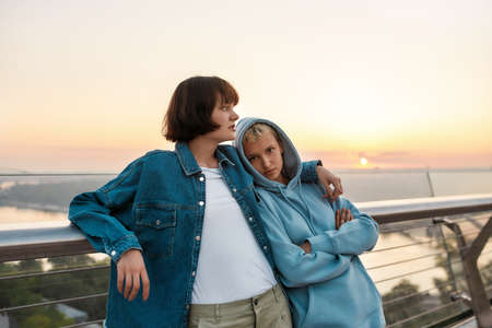 Young loving lesbian couple enjoying romantic moments while standing on the bridge and watching the...