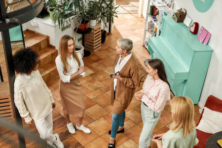 Women of different age and nationalities standing together in a bright spacy designers workshop