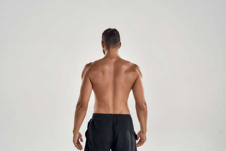 Rear view of muscular man with naked posing isolated over grey background, studio shotの写真素材
