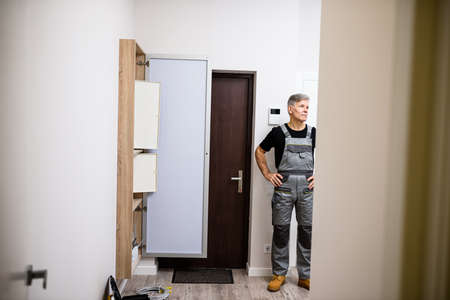 Full length shot of aged electrician, repairman in uniform standing and waiting colleague for...