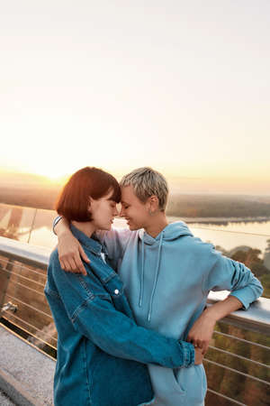 Young lesbian couple cuddling outdoors, Two women enjoying romantic moments together at sunrise