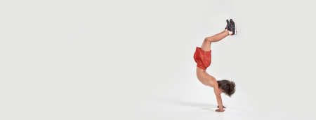 Full length shot of little sportive boy child in shorts jumping, showing strength and flexibility...