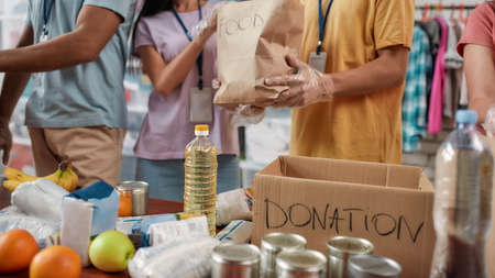 Cropped shot of male and female volunteers packing food donation for needy people, Young team working in charitable foundationの写真素材