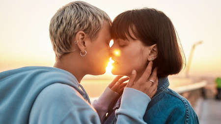 Two women kissing outdoors, Young lesbian couple enjoying romantic moments together at sunriseの写真素材
