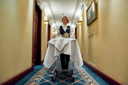 Feel the class. Full-length shot of waitress walking along the hall while delivering tray with food...