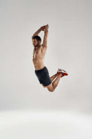 Young male athlete in high sideway jump with raised handsの写真素材