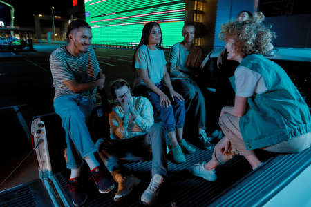 A close up of a group of young well-dressed friends of different nationalities sitting in a pick-ups...