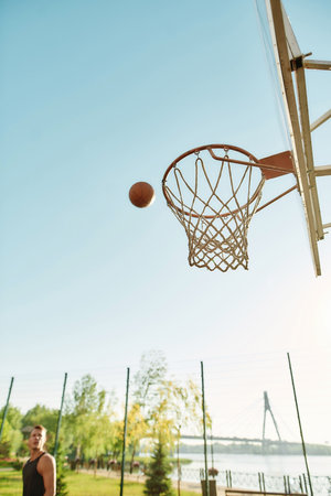 Close up of a basketball hoop with ball above outdoor playground with sky in the backgroundの写真素材
