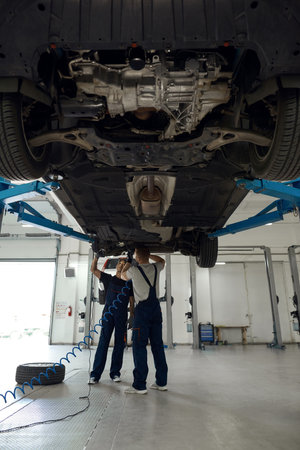 Technicians in uniform working with machine bottom