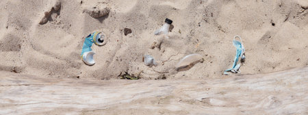 Dirty used plastic bottle, medical face mask and other garbage left by people on the beachの写真素材