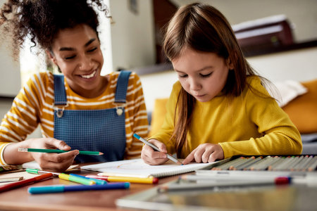 Small Steps. Caucasian little girl spending time with african american baby sitter. Kid is drawing,...
