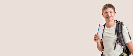 Happy disabled boy with Down syndrome wearing backpack smiling while holding two air tickets, standing isolated over white backgroundの写真素材