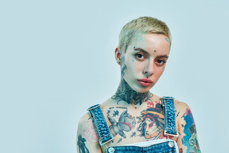 Close up of a white tattooed woman with piercing looking into a camera with her head slightly tiltedの写真素材