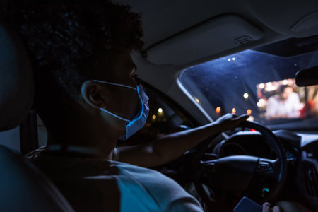 Young guy, male driver wearing protective mask while sitting in front seat of the car