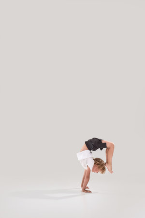 Full length shot of little playful boy child standing on his arms, showing flexibility isolated over...