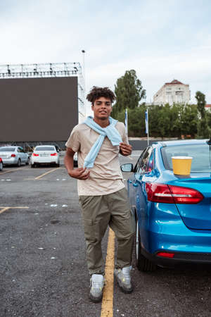 Young african american man standing near car at autocinema