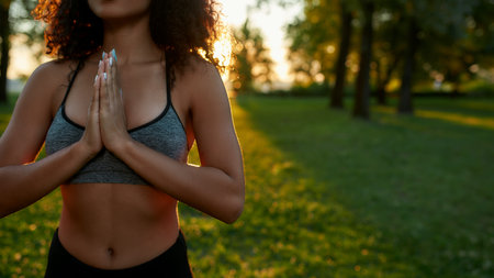 Practicing yoga in nature. Cropped shot of a young mixed race woman keeping palms together and meditating outdoors on a warm summer dayの写真素材