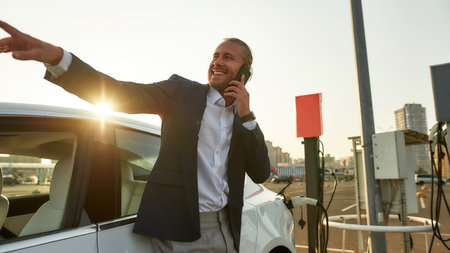 Smiling young caucasian man talking on phone on parkingの写真素材