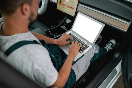 Young man doing computer diagnostics of electric autoの写真素材
