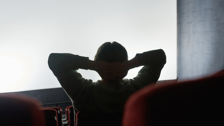Silhouetted view of relaxed guy leaning on the back of chair and keeping his hands over the head...