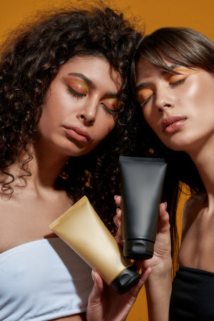 Satisfied women representing the cosmetic items with closed eyesの写真素材