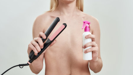 Hair straightener and styling spray in hands of manの写真素材