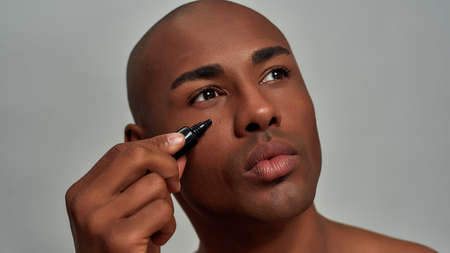 Black dropper bottle pressed under male eyeの写真素材