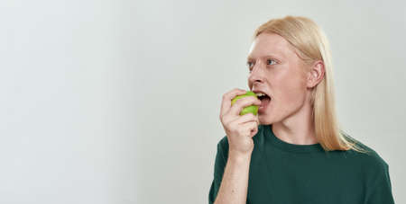 Handsome young caucasian man biting green juicy appleの写真素材