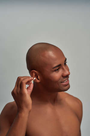 Multiethnic athletic male poking a cotton swab to an ear