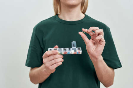 Young man holding week pill organizerの写真素材