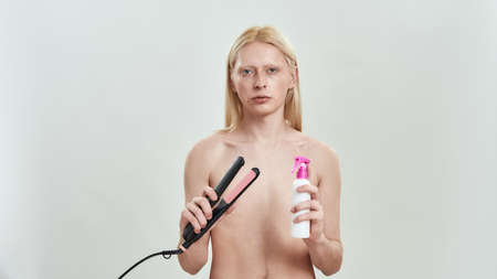 Young caucasian man holding tools for hair straighteningの写真素材