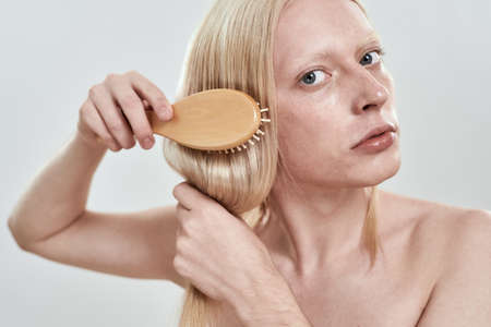 Portrait of young caucasian man grooming his long hairの写真素材