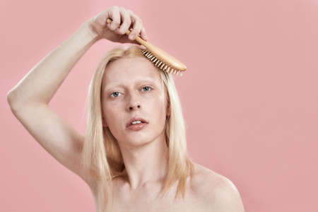 Young caucasian man combing his blond hair at head topの写真素材